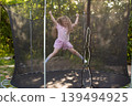 Child girl jumping on trampoline outdoors in the yard on summer vacation. 139494925