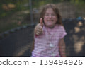Happy excited child girl sitting on trampoline outdoor showing thumb up sign 139494926