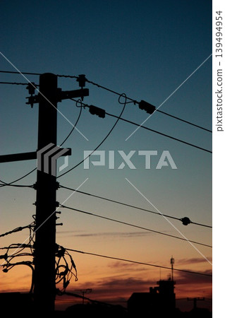 A telephone pole at dusk, its silhouette, and the sunset. A telephone pole at dusk, its silhouette, and the sunset. 139494954