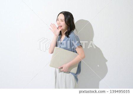 一名日本女子手持筆記型電腦，對著白色背景大聲喊叫。 139495035