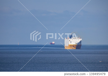 Large cargo ships navigate on calm waters near the coast on a sunny day in the afternoon Large cargo ships navigate on calm waters near the coast on a sunny day in the afternoon 139495479