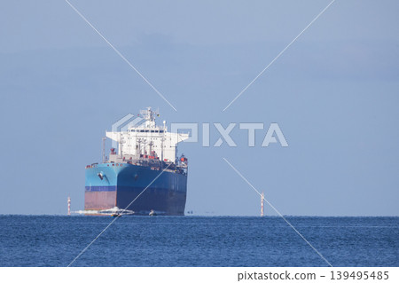 Large cargo ship travels across a calm sea near the coast during the day at a busy shipping route Large cargo ship travels across a calm sea near the coast during the day at a busy shipping route 139495485