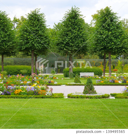 Scenic summer park landscape with vibrant floral arrangements and white bench 139495565