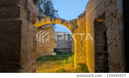 Eroded stone arch surrounded by stone brick walls 139495637