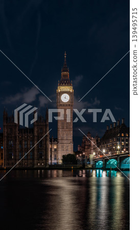 Bright clock face rises above the river and bridge at night, combining urban skyline with time concept and travel destination atmosphere. Bright clock face rises above the river and bridge at night, combining urban skyline with time concept and travel destination atmosphere. 139495715