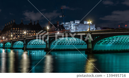 The arched river crossing shows historic structure detail, water reflections, and city background with clear night illumination. The arched river crossing shows historic structure detail, water reflections, and city background with clear night illumination. 139495716