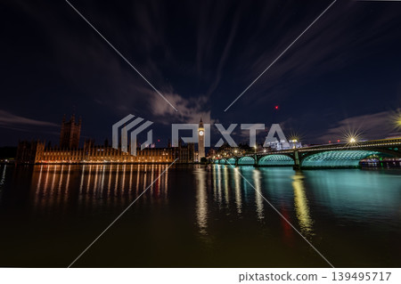 London United Kingdom panoramic night skyline Big Ben the Houses of Parliament and Westminster bridge illuminated clock tower riverside buildings reflection water. 139495717