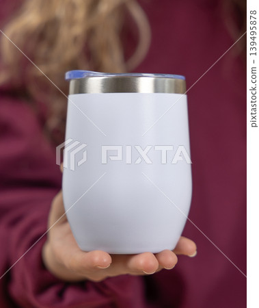 Blank white 12 oz wine tumbler mockup in female hand in dark red sweatshirt, copy space Blank white 12 oz wine tumbler mockup in female hand in dark red sweatshirt, copy space 139495878