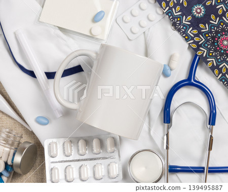 White 11 oz coffee mug mockup with medical accessories and scrub uniform top view, blank template White 11 oz coffee mug mockup with medical accessories and scrub uniform top view, blank template 139495887