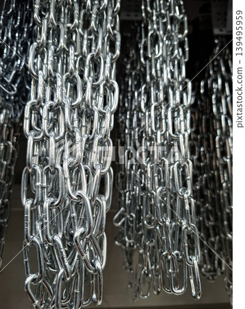 Close up of heavy duty steel chains hanging together. The chains show a repeating pattern and are used for construction and security tasks. The zinc coating gives them a shiny look. Close up of heavy duty steel chains hanging together. The chains show a repeating pattern and are used for construction and security tasks. The zinc coating gives them a shiny look. 139495959