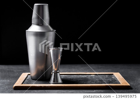 Cocktail shaker and jigger on dark bar background with copy space Cocktail shaker and jigger on dark bar background with copy space 139495975