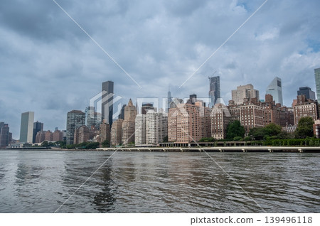New york, usa august 17,2024. Manhattan skyline seen across the east river on a cloudy day, featuring the united nations headquarters and urban architecture New york, usa august 17,2024. Manhattan skyline seen across the east river on a cloudy day, featuring the united nations headquarters and urban architecture 139496118