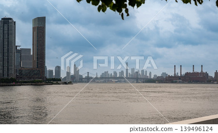 New york, usa august 17,2024. Manhattan skyline panorama with east river and williamsburg bridge under moody cloudy sky, iconic nyc waterfront view New york, usa august 17,2024. Manhattan skyline panorama with east river and williamsburg bridge under moody cloudy sky, iconic nyc waterfront view 139496124
