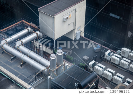 New york, usa august 17,2024. View of an urban rooftop with industrial hvac systems, air conditioning units, ventilation pipes, and an outdoor patio area New york, usa august 17,2024. View of an urban rooftop with industrial hvac systems, air conditioning units, ventilation pipes, and an outdoor patio area 139496131