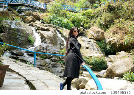 Beautiful woman in black coat posing at Darjeeling Rock Garden waterfall Beautiful woman in black coat posing at Darjeeling Rock Garden waterfall 139496585