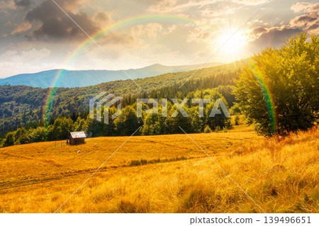 sunset over view of mountain meadow. countryside summertime landscape with beech forest on the grassy field on hill. cloudy sky. alpine background for travel through highland. weather with rainbow sunset over view of mountain meadow. countryside summertime landscape with beech forest on the grassy field on hill. cloudy sky. alpine background for travel through highland. weather with rainbow 139496651