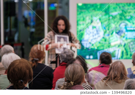 Older adults attend community presentation as woman presenter points to display during educational talk Older adults attend community presentation as woman presenter points to display during educational talk 139496820