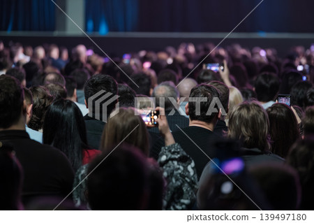 Audience at live event recording performance with smartphones, crowd watching concert from seats Audience at live event recording performance with smartphones, crowd watching concert from seats 139497180