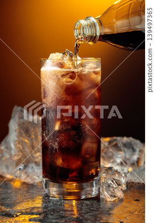 Cola is poured into a glass with ice. Cola is poured into a glass with ice. 139497365