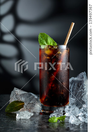 Cola with ice and mint in misted glass on a black background. Cola with ice and mint in misted glass on a black background. 139497367