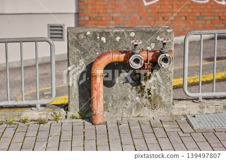 Rusty pipe connected to a concrete wall 139497807