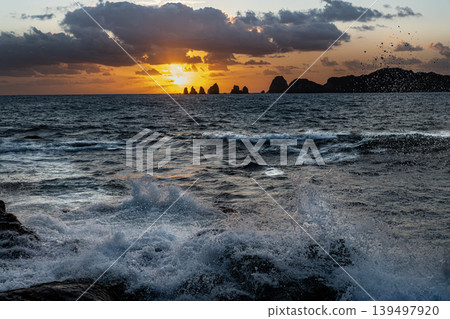 A view of the sunrise over the Nanatsu-iwa rocks off the coast of Hyuga-nada Sea and the crashing waves from Inozakibana Park Campground in Nichinan City, Miyazaki Prefecture. 139497920