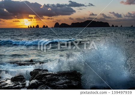 A view of the sunrise over the Nanatsu-iwa rocks off the coast of Hyuga-nada Sea and the crashing waves from Inozakibana Park Campground in Nichinan City, Miyazaki Prefecture. A view of the sunrise over the Nanatsu-iwa rocks off the coast of Hyuga-nada Sea and the crashing waves from Inozakibana Park Campground in Nichinan City, Miyazaki Prefecture. 139497939