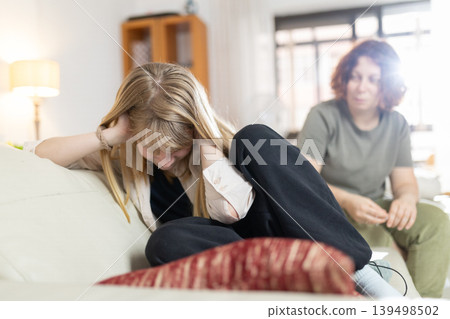 Teenager having emotional problem with mother sitting on sofa Teenager having emotional problem with mother sitting on sofa 139498502