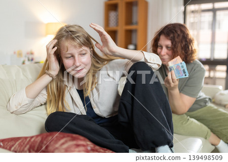 Mother offering money to daughter who is refusing it Mother offering money to daughter who is refusing it 139498509