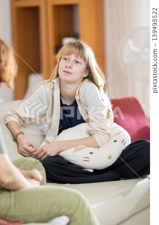 Young person thoughtfully listening during a serious conversation at home Young person thoughtfully listening during a serious conversation at home 139498522