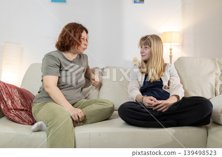 Mother and daughter having serious conversation on sofa Mother and daughter having serious conversation on sofa 139498523