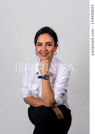 A woman wearing a white shirt and black pants is smiling and holding her wrist A woman wearing a white shirt and black pants is smiling and holding her wrist 139498605