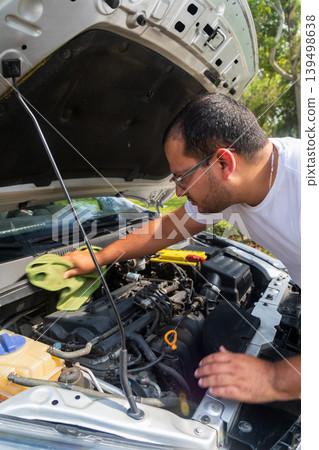 A man is cleaning the engine of a car A man is cleaning the engine of a car 139498638