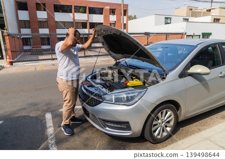 A man is standing next to a car with the hood up A man is standing next to a car with the hood up 139498644