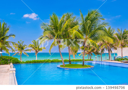 landscape with an infinity swimming pool on beach with palm trees by the sea in luxury hotel in a resort in tropics in Asia in summer landscape with an infinity swimming pool on beach with palm trees by the sea in luxury hotel in a resort in tropics in Asia in summer 139498706