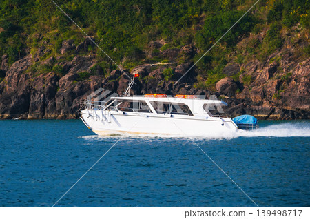 A high-speed white tourist speedboat sails through sea near an island in Vietnam. Motor boat in river in Asia A high-speed white tourist speedboat sails through sea near an island in Vietnam. Motor boat in river in Asia 139498717