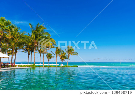 infinity pool by the beach by the sea under palm trees in luxury hotel in resort in the tropics for summer holidays infinity pool by the beach by the sea under palm trees in luxury hotel in resort in the tropics for summer holidays 139498719