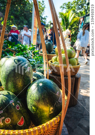 Watermelons with funny faces painted on them, in bamboo baskets at a tropical outdoor market. 139498919