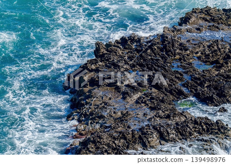 蔚藍的大海拍打著崎嶇的岩石海岸。 139498976