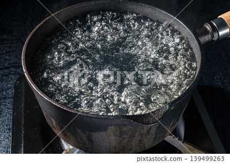 A close-up of a cast iron pot used for deep-frying in boiling oil. A close-up of a cast iron pot used for deep-frying in boiling oil. 139499263