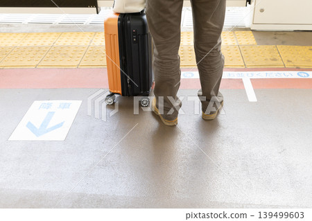 Feet of someone holding a suitcase on the train platform 139499603