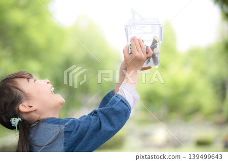 "I caught one!" A girl enjoys insect collecting, discovering and observing insects like rhinoceros beetles. 139499643