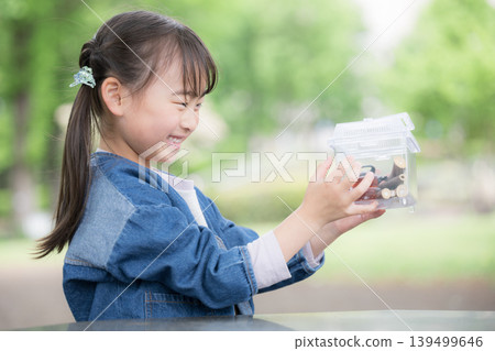 "I caught one!" A girl enjoys insect collecting, discovering and observing insects like rhinoceros beetles. 139499646