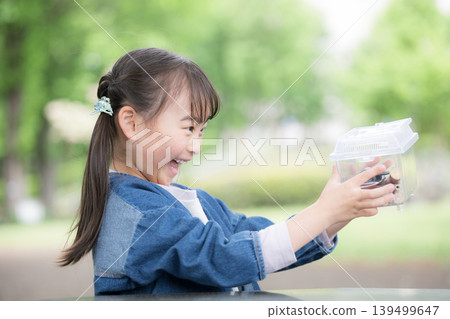 "I caught one!" A girl enjoys insect collecting, discovering and observing insects like rhinoceros beetles. 139499647