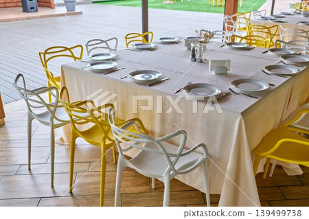 Restaurant dining area with yellow and white chairs. 139499738