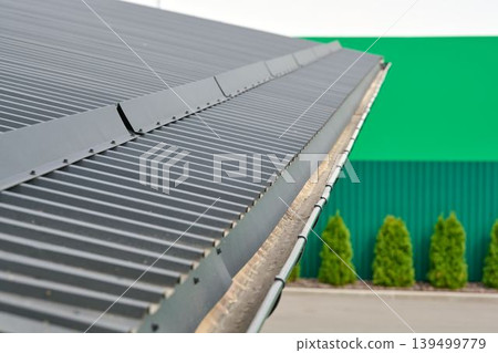 Corrugated metal roof a modern building with gutter on green background. 139499779