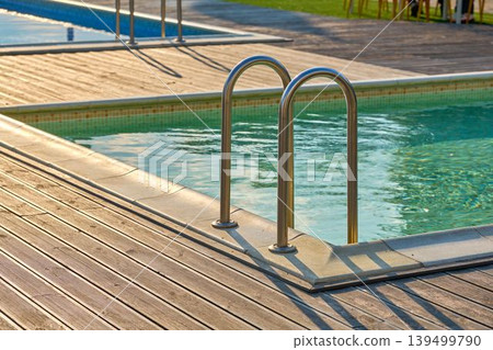 Close-up of a section of the swimming pool with a wooden deck and a ladder to enter 139499790