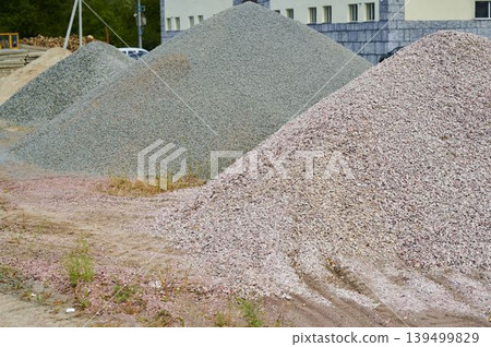 Piles of gravel sit on a construction site under a bright sky in the afternoon light Piles of gravel sit on a construction site under a bright sky in the afternoon light 139499829