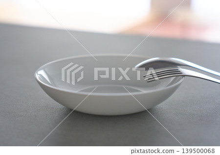 White dishes and cutlery placed on the table White dishes and cutlery placed on the table 139500068