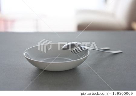 White dishes and cutlery placed on the table 139500069